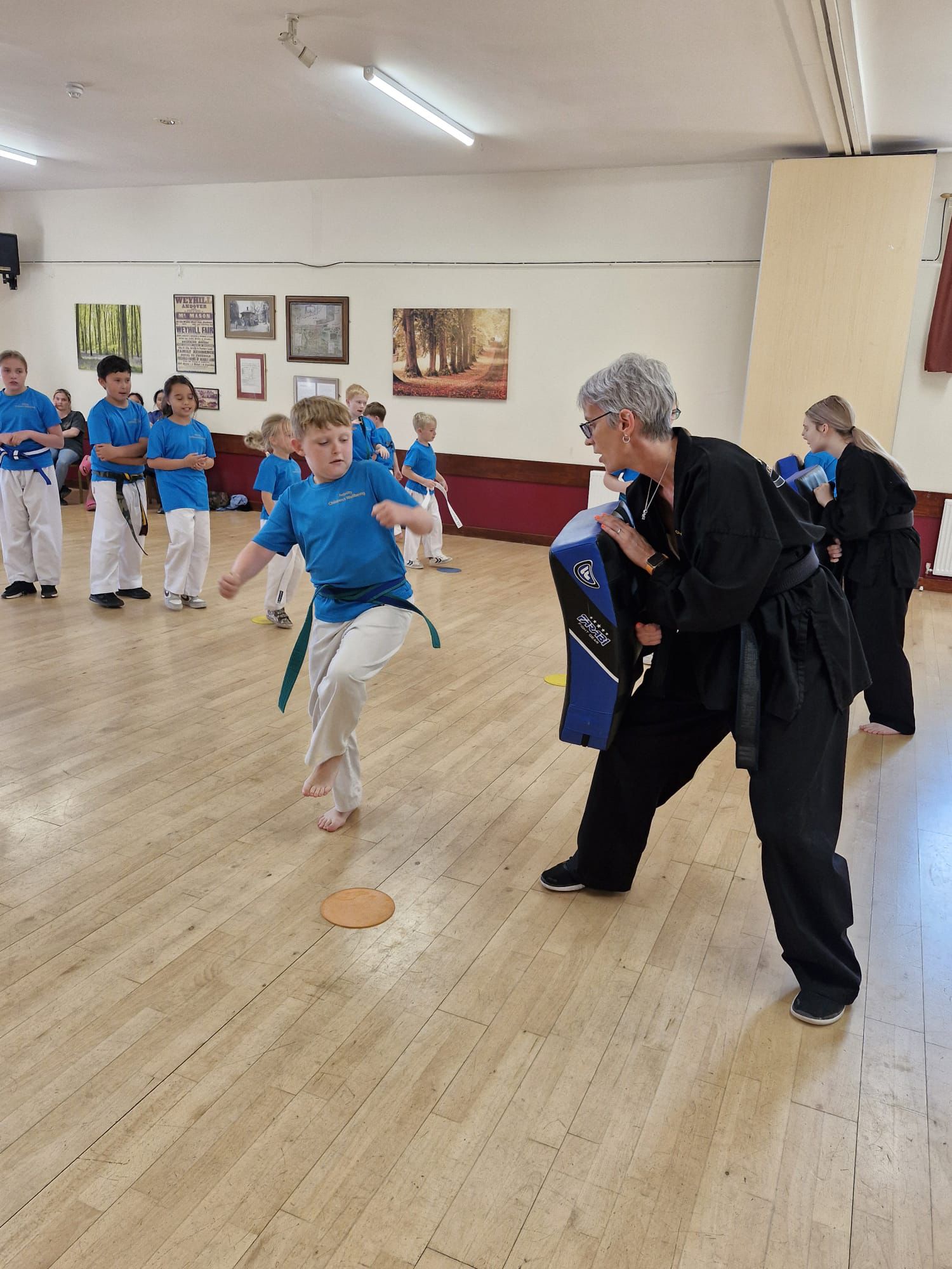 Child kicking a pad while Natalie Bryden holds it